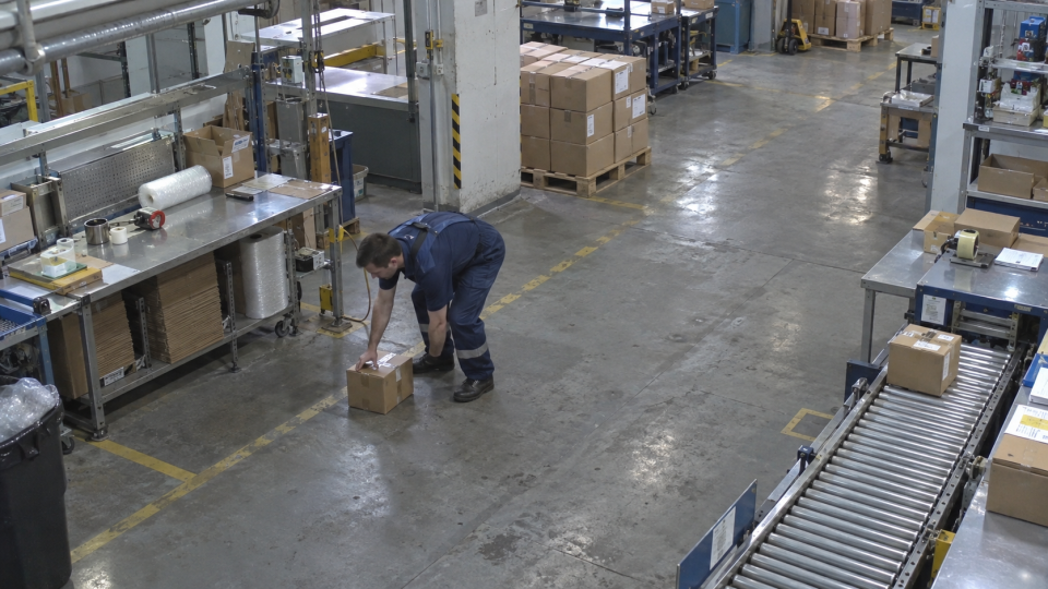 Workshop frame with a worker bending to pick up a carton