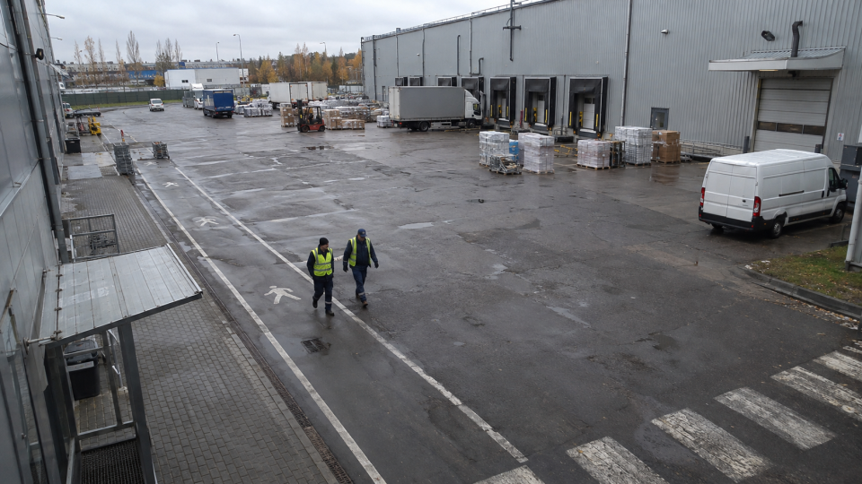 Warehouse yard frame with workers in hi-vis vests and a delivery van